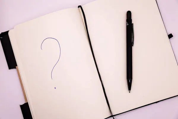 Beyaz arkaplanda kalem ve soru işareti olan defter. Üst görünüm.