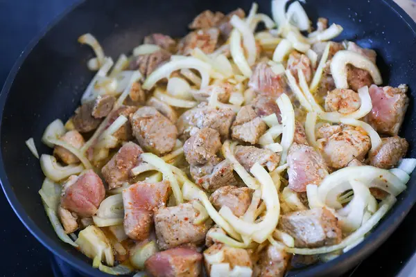 Kızartma tavasında soğan ve baharatlı domuz eti. Kapat.