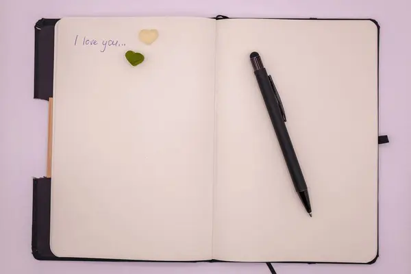 Mesajını, kalbini ve beyaz arka planda siyah bir kalemi olan bir defter. Sevgililer Günü