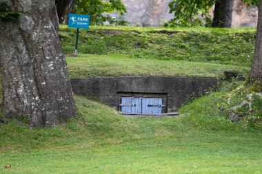 Ahşap kapılı ve yeşil çimenlikli eski sığınağa giriş.
