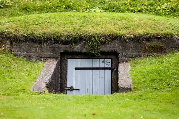 Eski ahşap kapı. Yeşil çim alanındaki bir sığınağa giriş.