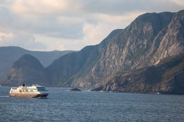 Norveç ve İskandinavya 'daki dağların ve bulutların arka planında, denizde bir gemi gezisi.