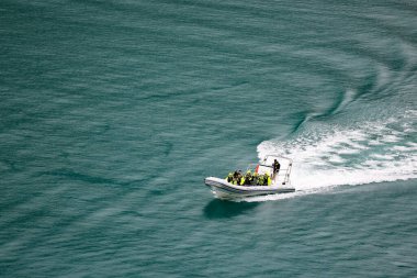 Beyaz köpükle denizde yüzen bir motorlu teknenin hava görüntüsü.