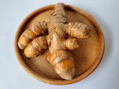 Servis panosundaki taze zerdeçal kökü. Zerdeçal öncelikle Asya mutfağında ve potansiyel sağlık yararları için yemek pişirmede bir baharat olarak kullanılır. Zemin baharatı ve taze kökler gibi çeşitli şekillerde de kullanılır.