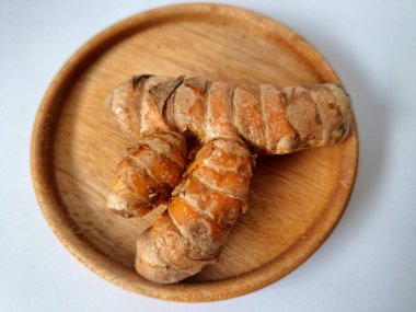 Servis panosundaki taze zerdeçal kökü. Zerdeçal öncelikle Asya mutfağında ve potansiyel sağlık yararları için yemek pişirmede bir baharat olarak kullanılır. Zemin baharatı ve taze kökler gibi çeşitli şekillerde de kullanılır.