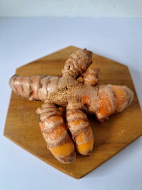 Servis panosundaki taze zerdeçal kökü. Zerdeçal öncelikle Asya mutfağında ve potansiyel sağlık yararları için yemek pişirmede bir baharat olarak kullanılır. Zemin baharatı ve taze kökler gibi çeşitli şekillerde de kullanılır.