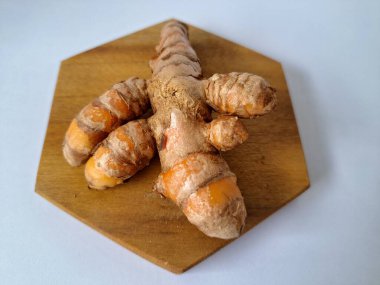 Servis panosundaki taze zerdeçal kökü. Zerdeçal öncelikle Asya mutfağında ve potansiyel sağlık yararları için yemek pişirmede bir baharat olarak kullanılır. Zemin baharatı ve taze kökler gibi çeşitli şekillerde de kullanılır.