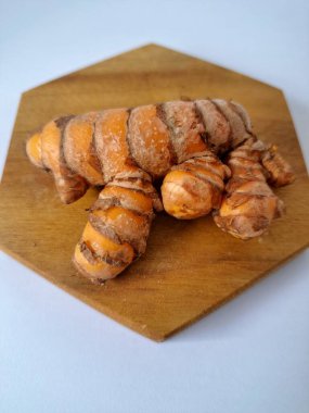 Servis panosundaki taze zerdeçal kökü. Zerdeçal öncelikle Asya mutfağında ve potansiyel sağlık yararları için yemek pişirmede bir baharat olarak kullanılır. Zemin baharatı ve taze kökler gibi çeşitli şekillerde de kullanılır.