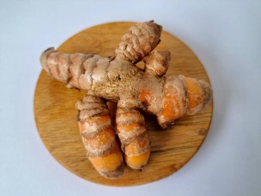 Servis panosundaki taze zerdeçal kökü. Zerdeçal öncelikle Asya mutfağında ve potansiyel sağlık yararları için yemek pişirmede bir baharat olarak kullanılır. Zemin baharatı ve taze kökler gibi çeşitli şekillerde de kullanılır.