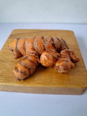 Servis panosundaki taze zerdeçal kökü. Zerdeçal öncelikle Asya mutfağında ve potansiyel sağlık yararları için yemek pişirmede bir baharat olarak kullanılır. Zemin baharatı ve taze kökler gibi çeşitli şekillerde de kullanılır.