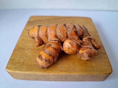 Servis panosundaki taze zerdeçal kökü. Zerdeçal öncelikle Asya mutfağında ve potansiyel sağlık yararları için yemek pişirmede bir baharat olarak kullanılır. Zemin baharatı ve taze kökler gibi çeşitli şekillerde de kullanılır.