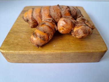 Servis panosundaki taze zerdeçal kökü. Zerdeçal öncelikle Asya mutfağında ve potansiyel sağlık yararları için yemek pişirmede bir baharat olarak kullanılır. Zemin baharatı ve taze kökler gibi çeşitli şekillerde de kullanılır.