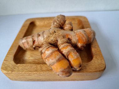 Servis panosundaki taze zerdeçal kökü. Zerdeçal öncelikle Asya mutfağında ve potansiyel sağlık yararları için yemek pişirmede bir baharat olarak kullanılır. Zemin baharatı ve taze kökler gibi çeşitli şekillerde de kullanılır.