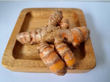 Servis panosundaki taze zerdeçal kökü. Zerdeçal öncelikle Asya mutfağında ve potansiyel sağlık yararları için yemek pişirmede bir baharat olarak kullanılır. Zemin baharatı ve taze kökler gibi çeşitli şekillerde de kullanılır.