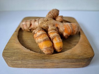 Servis panosundaki taze zerdeçal kökü. Zerdeçal öncelikle Asya mutfağında ve potansiyel sağlık yararları için yemek pişirmede bir baharat olarak kullanılır. Zemin baharatı ve taze kökler gibi çeşitli şekillerde de kullanılır.