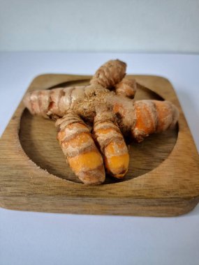 Servis panosundaki taze zerdeçal kökü. Zerdeçal öncelikle Asya mutfağında ve potansiyel sağlık yararları için yemek pişirmede bir baharat olarak kullanılır. Zemin baharatı ve taze kökler gibi çeşitli şekillerde de kullanılır.