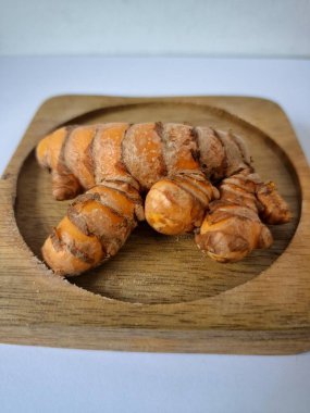 Servis panosundaki taze zerdeçal kökü. Zerdeçal öncelikle Asya mutfağında ve potansiyel sağlık yararları için yemek pişirmede bir baharat olarak kullanılır. Zemin baharatı ve taze kökler gibi çeşitli şekillerde de kullanılır.