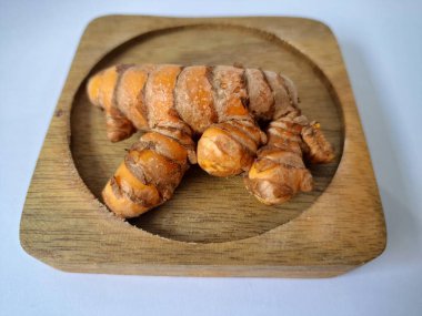 Servis panosundaki taze zerdeçal kökü. Zerdeçal öncelikle Asya mutfağında ve potansiyel sağlık yararları için yemek pişirmede bir baharat olarak kullanılır. Zemin baharatı ve taze kökler gibi çeşitli şekillerde de kullanılır.