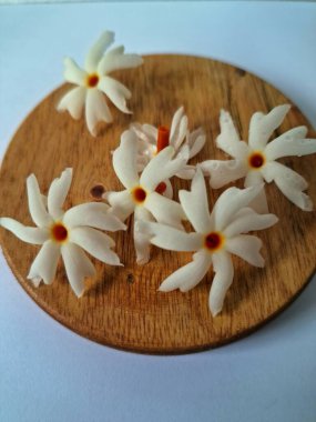 Servis tahtasındaki taze parijat çiçekleri. Çeşitli kullanımları var, hem tıbbi hem de kültürel. Ayurvedic tıpta ateş, öksürük ve soğuk algınlığını tedavi etmek için kullanılır. Çiçekler Hindu ayinlerinde ve tanrılara adak olarak da kullanılır.