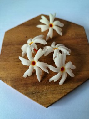 Servis tahtasındaki taze parijat çiçekleri. Çeşitli kullanımları var, hem tıbbi hem de kültürel. Ayurvedic tıpta ateş, öksürük ve soğuk algınlığını tedavi etmek için kullanılır. Çiçekler Hindu ayinlerinde ve tanrılara adak olarak da kullanılır.