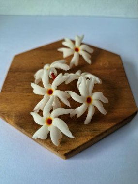 Servis tahtasındaki taze parijat çiçekleri. Çeşitli kullanımları var, hem tıbbi hem de kültürel. Ayurvedic tıpta ateş, öksürük ve soğuk algınlığını tedavi etmek için kullanılır. Çiçekler Hindu ayinlerinde ve tanrılara adak olarak da kullanılır.