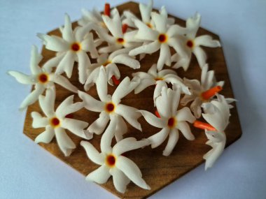 Servis tahtasındaki taze parijat çiçekleri. Çeşitli kullanımları var, hem tıbbi hem de kültürel. Ayurvedic tıpta ateş, öksürük ve soğuk algınlığını tedavi etmek için kullanılır. Çiçekler Hindu ayinlerinde ve tanrılara adak olarak da kullanılır.