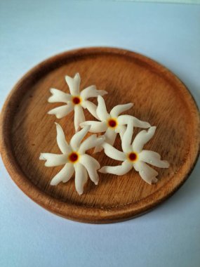 Servis tahtasındaki taze parijat çiçekleri. Çeşitli kullanımları var, hem tıbbi hem de kültürel. Ayurvedic tıpta ateş, öksürük ve soğuk algınlığını tedavi etmek için kullanılır. Çiçekler Hindu ayinlerinde ve tanrılara adak olarak da kullanılır.