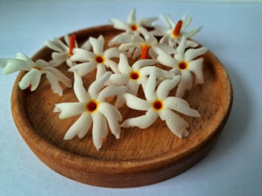 Servis tahtasındaki taze parijat çiçekleri. Çeşitli kullanımları var, hem tıbbi hem de kültürel. Ayurvedic tıpta ateş, öksürük ve soğuk algınlığını tedavi etmek için kullanılır. Çiçekler Hindu ayinlerinde ve tanrılara adak olarak da kullanılır.