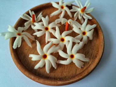 Servis tahtasındaki taze parijat çiçekleri. Çeşitli kullanımları var, hem tıbbi hem de kültürel. Ayurvedic tıpta ateş, öksürük ve soğuk algınlığını tedavi etmek için kullanılır. Çiçekler Hindu ayinlerinde ve tanrılara adak olarak da kullanılır.