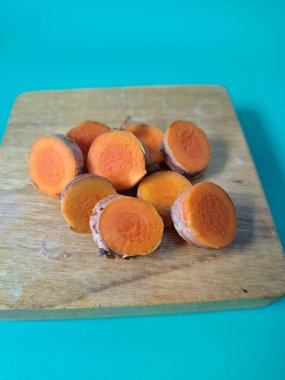 Servis tahtasında taze zerdeçal yumrusu dilimleri. Bu baharat Asya mutfağında yaygın olarak kullanılır, özellikle köri gibi yemeklerde tat ve renk için. Zerdeçal ayrıca aktif bileşik curkiminle birlikte tıbbi özelliklere de sahiptir.