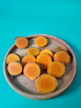 Servis tahtasında taze zerdeçal yumrusu dilimleri. Zerdeçal birçok sağlık yararına sahip bir bitkisel bitkidir. Zerdeçal sıklıkla geleneksel tıpta ve yemek pişirmede bir tat ve doğal renklendirme olarak kullanılır.