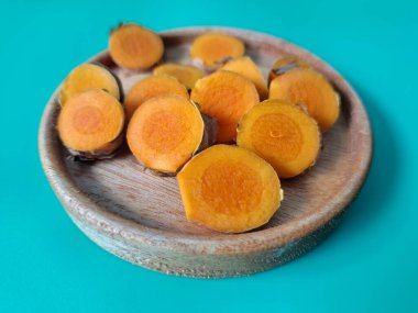 Servis tahtasında taze zerdeçal yumrusu dilimleri. Zerdeçal birçok sağlık yararına sahip bir bitkisel bitkidir. Zerdeçal sıklıkla geleneksel tıpta ve yemek pişirmede bir tat ve doğal renklendirme olarak kullanılır.