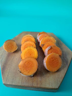 Servis tahtasında taze zerdeçal yumrusu dilimleri. Bu baharat Asya mutfağında yaygın olarak kullanılır, özellikle köri gibi yemeklerde tat ve renk için. Zerdeçal ayrıca aktif bileşik curkiminle birlikte tıbbi özelliklere de sahiptir.