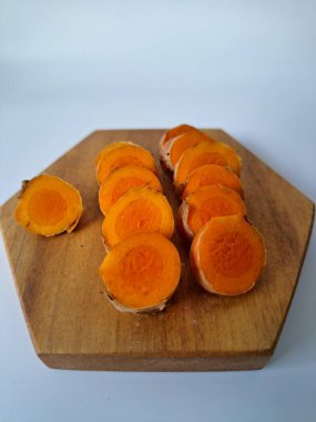 Servis tahtasında taze zerdeçal yumrusu dilimleri. Zerdeçal birçok sağlık yararına sahip bir bitkisel bitkidir. Zerdeçal sıklıkla geleneksel tıpta ve yemek pişirmede bir tat ve doğal renklendirme olarak kullanılır.