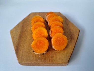 Servis tahtasında taze zerdeçal yumrusu dilimleri. Zerdeçal birçok sağlık yararına sahip bir bitkisel bitkidir. Zerdeçal sıklıkla geleneksel tıpta ve yemek pişirmede bir tat ve doğal renklendirme olarak kullanılır.