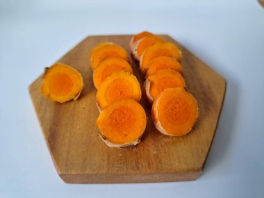 Servis tahtasında taze zerdeçal yumrusu dilimleri. Bu baharat Asya mutfağında yaygın olarak kullanılır, özellikle köri gibi yemeklerde tat ve renk için. Zerdeçal ayrıca aktif bileşik curkiminle birlikte tıbbi özelliklere de sahiptir.