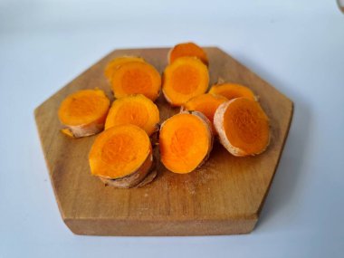 Servis tahtasında taze zerdeçal yumrusu dilimleri. Zerdeçal birçok sağlık yararına sahip bir bitkisel bitkidir. Zerdeçal sıklıkla geleneksel tıpta ve yemek pişirmede bir tat ve doğal renklendirme olarak kullanılır.