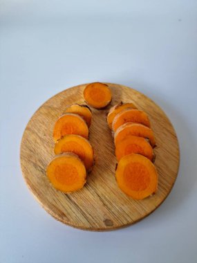 Servis tahtasında taze zerdeçal yumrusu dilimleri. Zerdeçal birçok sağlık yararına sahip bir bitkisel bitkidir. Zerdeçal sıklıkla geleneksel tıpta ve yemek pişirmede bir tat ve doğal renklendirme olarak kullanılır.