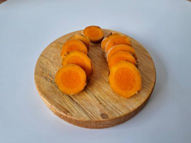 Servis tahtasında taze zerdeçal yumrusu dilimleri. Zerdeçal birçok sağlık yararına sahip bir bitkisel bitkidir. Zerdeçal sıklıkla geleneksel tıpta ve yemek pişirmede bir tat ve doğal renklendirme olarak kullanılır.