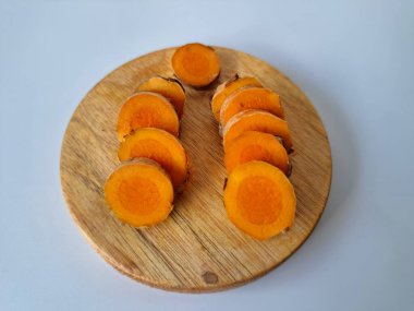 Servis tahtasında taze zerdeçal yumrusu dilimleri. Zerdeçal birçok sağlık yararına sahip bir bitkisel bitkidir. Zerdeçal sıklıkla geleneksel tıpta ve yemek pişirmede bir tat ve doğal renklendirme olarak kullanılır.