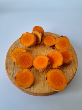 Servis tahtasında taze zerdeçal yumrusu dilimleri. Zerdeçal birçok sağlık yararına sahip bir bitkisel bitkidir. Zerdeçal sıklıkla geleneksel tıpta ve yemek pişirmede bir tat ve doğal renklendirme olarak kullanılır.