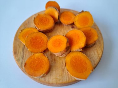 Servis tahtasında taze zerdeçal yumrusu dilimleri. Zerdeçal birçok sağlık yararına sahip bir bitkisel bitkidir. Zerdeçal sıklıkla geleneksel tıpta ve yemek pişirmede bir tat ve doğal renklendirme olarak kullanılır.