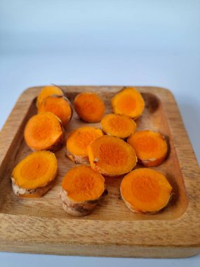 Servis tahtasında taze zerdeçal yumrusu dilimleri. Bu baharat Asya mutfağında yaygın olarak kullanılır, özellikle köri gibi yemeklerde tat ve renk için. Zerdeçal ayrıca aktif bileşik curkiminle birlikte tıbbi özelliklere de sahiptir.