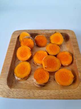 Servis tahtasında taze zerdeçal yumrusu dilimleri. Zerdeçal birçok sağlık yararına sahip bir bitkisel bitkidir. Zerdeçal sıklıkla geleneksel tıpta ve yemek pişirmede bir tat ve doğal renklendirme olarak kullanılır.