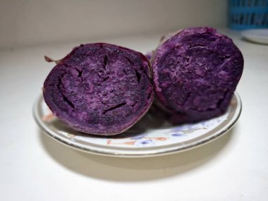 Küçük bir tabakta dilimlenmiş mor tatlı patates. Mor tatlı patatesler canlı mor etli kök sebzelerdir, yüksek antosiyanin pigmenti içeriğinin bir sonucu, aynı antioksidan yaban mersinleri ve kırmızı lahanada da bulunur.