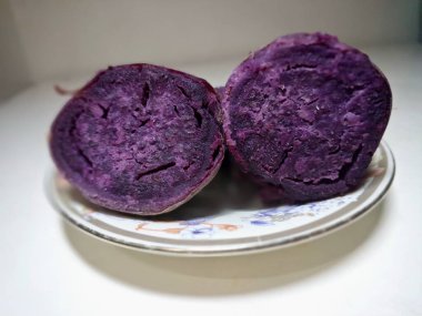 Küçük bir tabakta dilimlenmiş mor tatlı patates. Mor tatlı patatesler canlı mor etli kök sebzelerdir, yüksek antosiyanin pigmenti içeriğinin bir sonucu, aynı antioksidan yaban mersinleri ve kırmızı lahanada da bulunur.