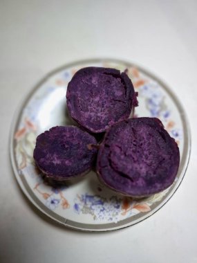 Küçük bir tabakta dilimlenmiş mor tatlı patates. Mor tatlı patatesler canlı mor etli kök sebzelerdir, yüksek antosiyanin pigmenti içeriğinin bir sonucu, aynı antioksidan yaban mersinleri ve kırmızı lahanada da bulunur.