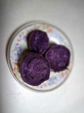 Küçük bir tabakta dilimlenmiş mor tatlı patates. Mor tatlı patatesler canlı mor etli kök sebzelerdir, yüksek antosiyanin pigmenti içeriğinin bir sonucu, aynı antioksidan yaban mersinleri ve kırmızı lahanada da bulunur.