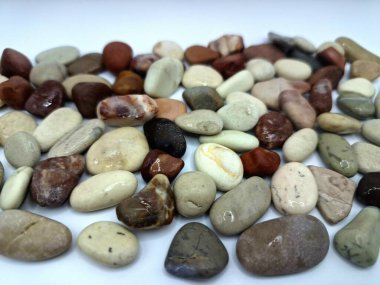 Beyaz arka planda izole edilmiş renkli çakıl taşı. Renkli çakıl taşlarının çeşitli dekoratif ve işlevsel kullanımları vardır, özellikle bahçe düzenlemeleri ve bahçecilikte.