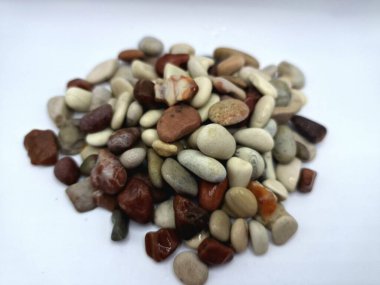 Beyaz arka planda izole edilmiş renkli çakıl taşı. Renkli çakıl taşlarının çeşitli dekoratif ve işlevsel kullanımları vardır, özellikle bahçe düzenlemeleri ve bahçecilikte.